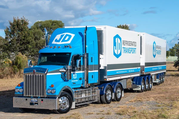 A blue JD Kenworth hauling a refrigerated B-double